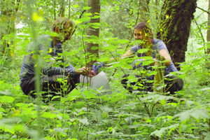 two researchers kneeling in a wooded area