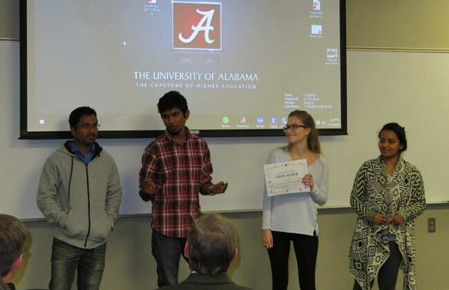 four students standing at the front of a class
